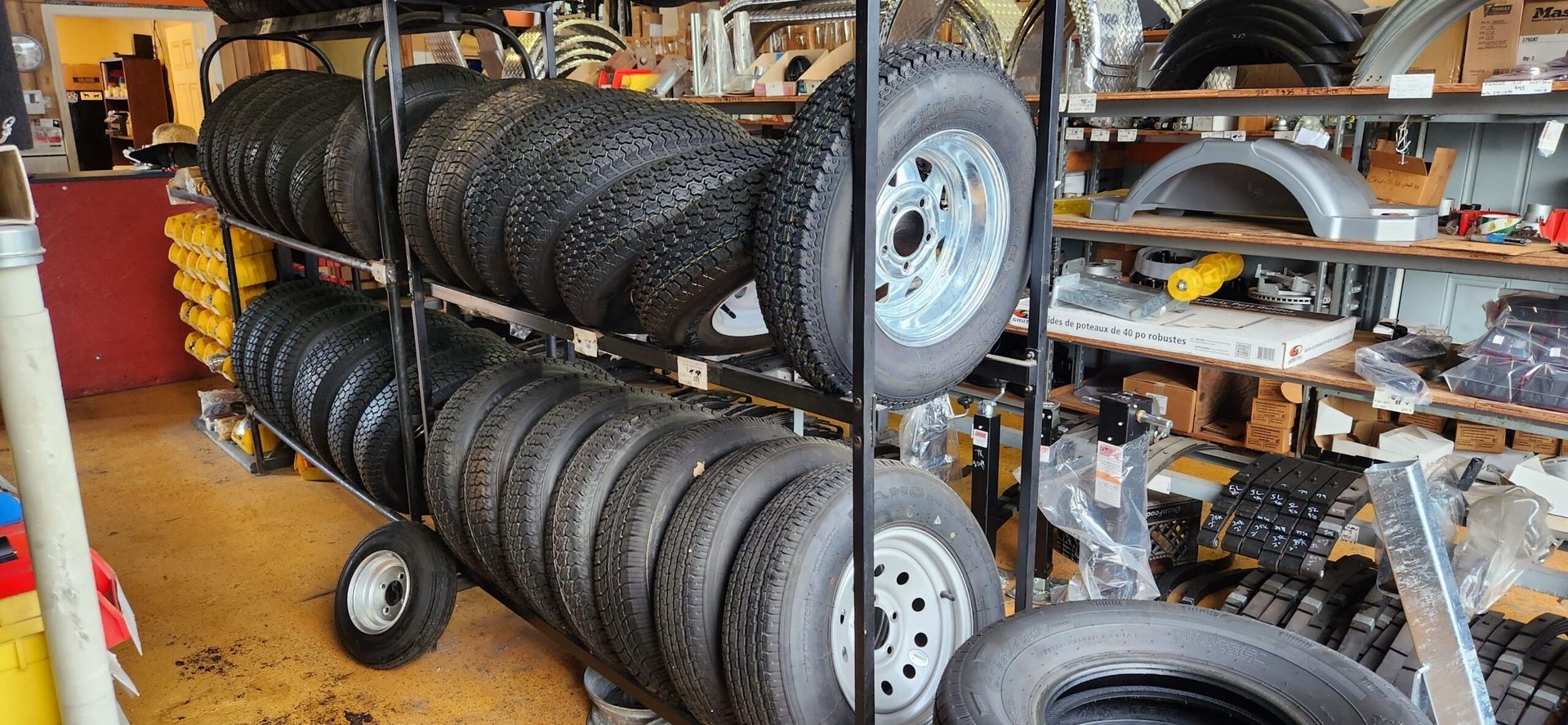 Shelves in a garage stocked with stacked car tires and wheels, with tools and parts around them