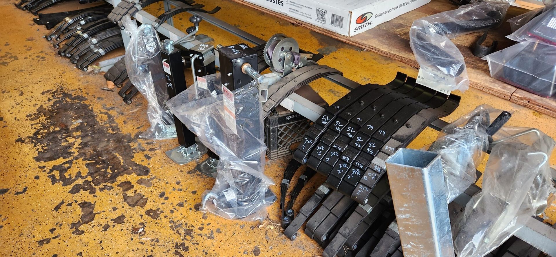 Stacked black mechanical parts wrapped in plastic on a yellow floor, with scattered debris nearby
