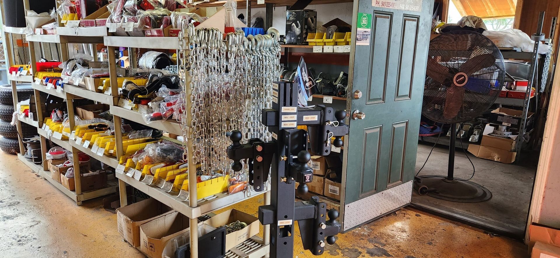 Hardware store aisle with shelves of tools, hanging items, and a row of garden tools on display