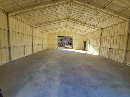 Interior of a large metal building with spray foam insulation on walls and ceiling; concrete floor.