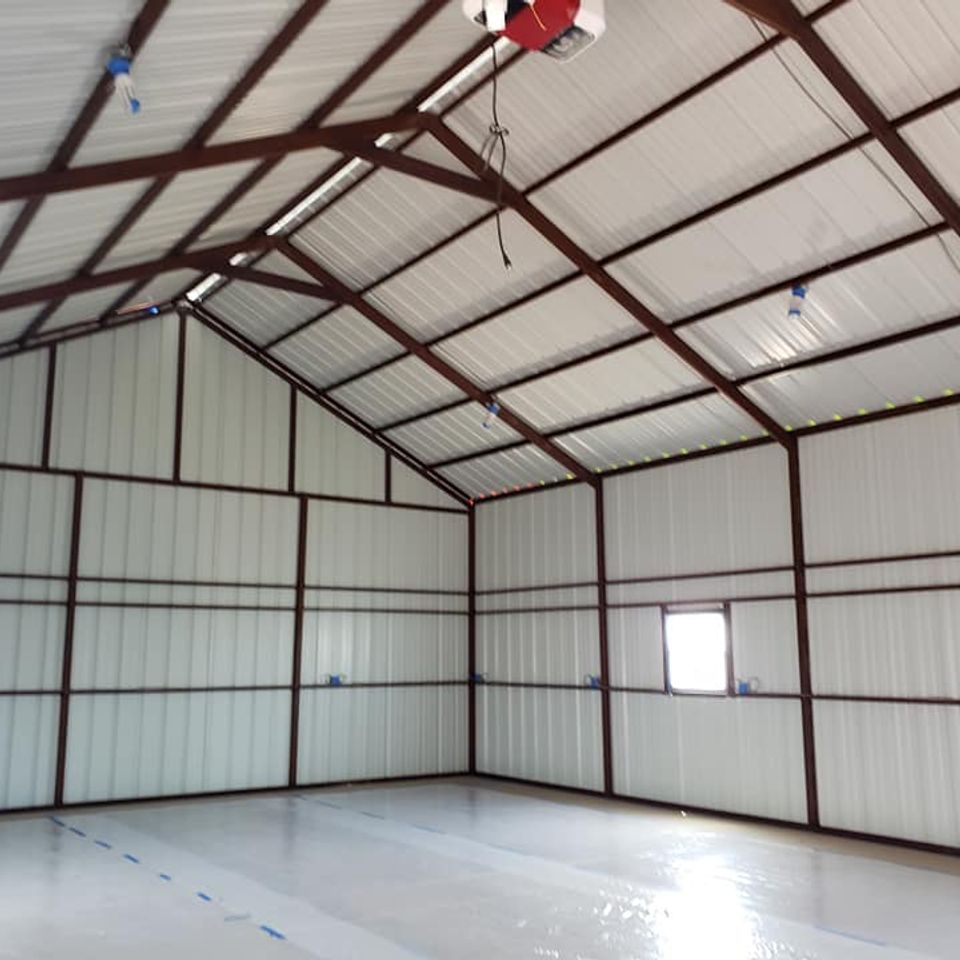 Interior of a metal building with white walls, roof, and a shiny, light gray floor. Brown metal beams frame the walls and ceiling.