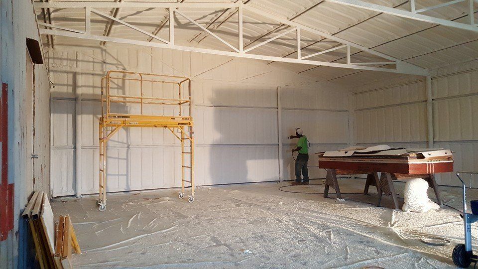 Interior of a metal building with insulation, a person working, scaffolding, and a piano.