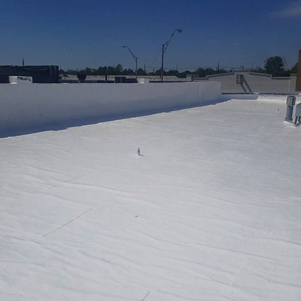 White commercial flat roof with low parapet walls, blue sky.