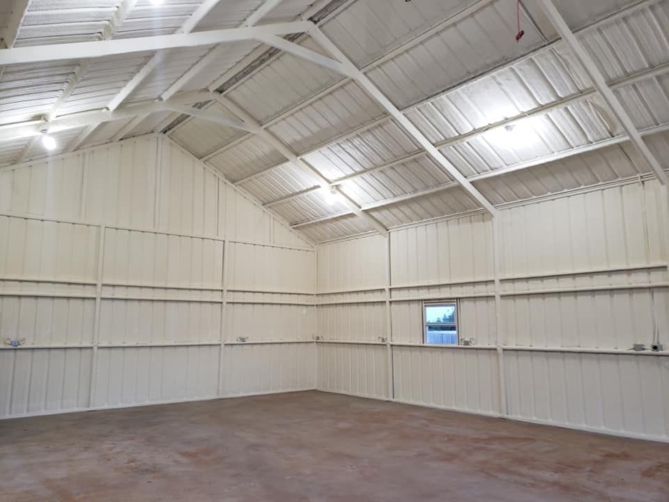 Interior of a large, empty metal building with light-colored insulation on the walls and ceiling.
