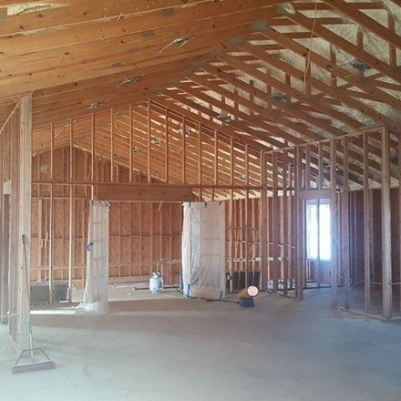 Interior view of a building under construction, showing wooden framing and exposed beams.