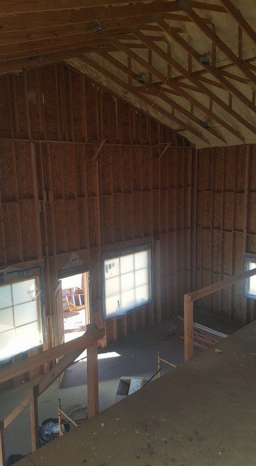 Interior of a building under construction, framed walls and windows visible.
