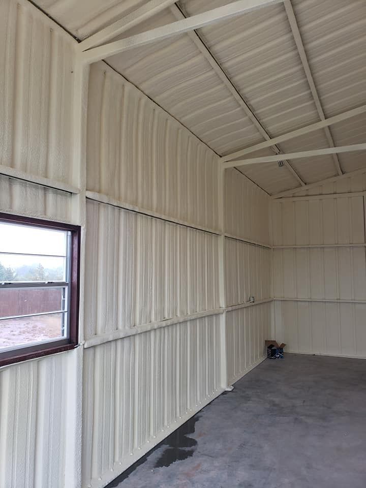 Interior of a metal building with a window, coated in white insulation.