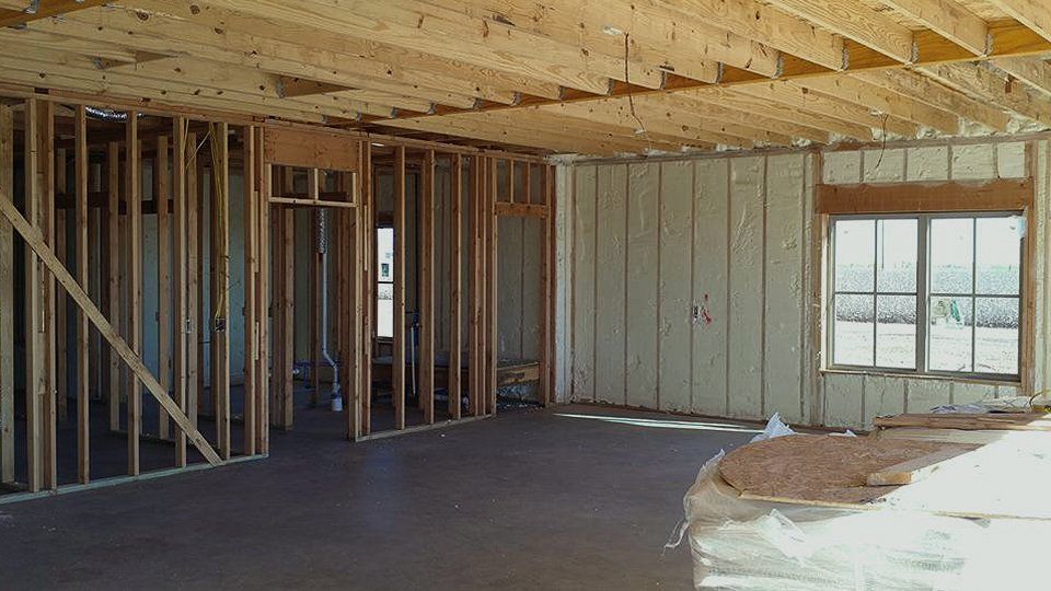 Interior of a building under construction, showing wooden frames, concrete floor, and window.