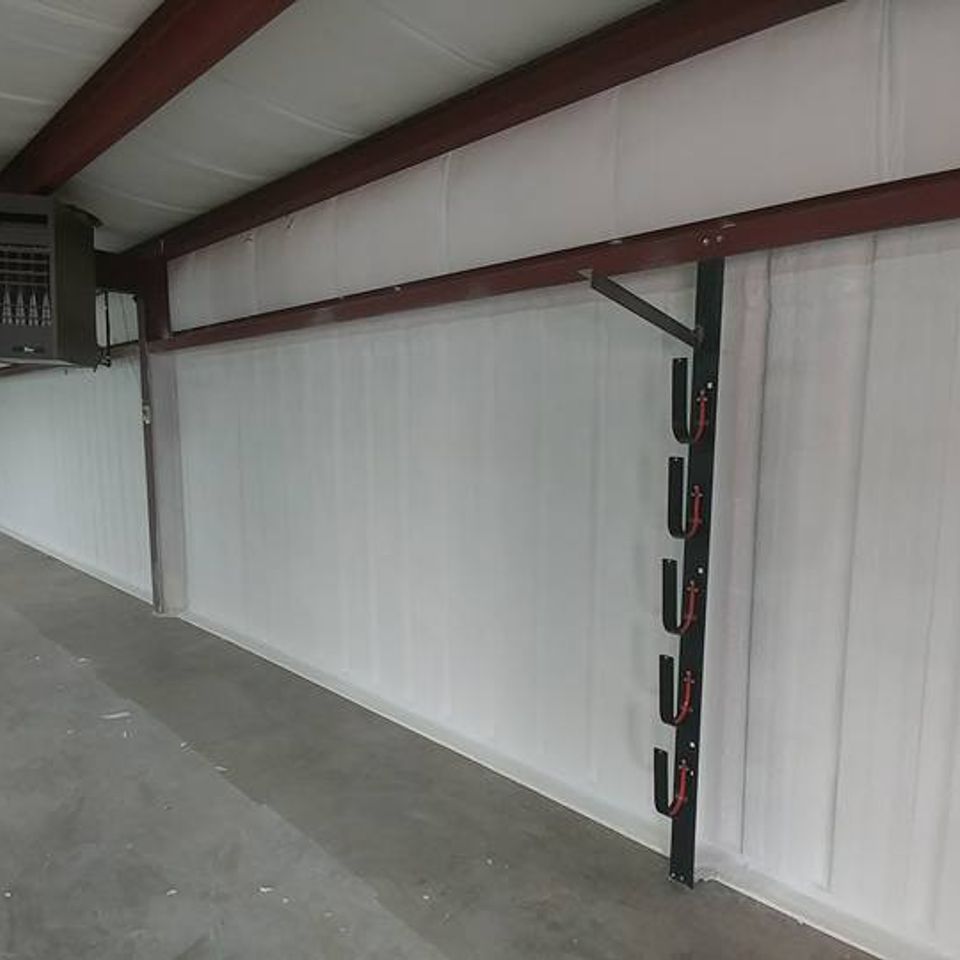 Interior of a large building with white walls, a metal frame ceiling, and a row of red and black racks.