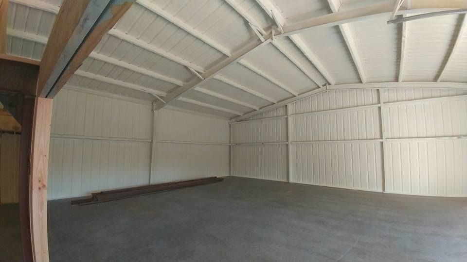 Interior of a white-walled metal building with a concrete floor and arched ceiling.