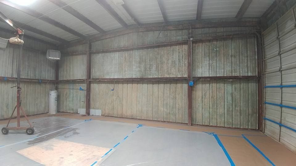 Interior of a metal industrial building with gray concrete floor, metal walls, and exposed beams.