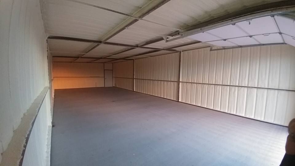 Interior of a large, empty storage unit. Beige walls and ceiling with a dark gray floor.