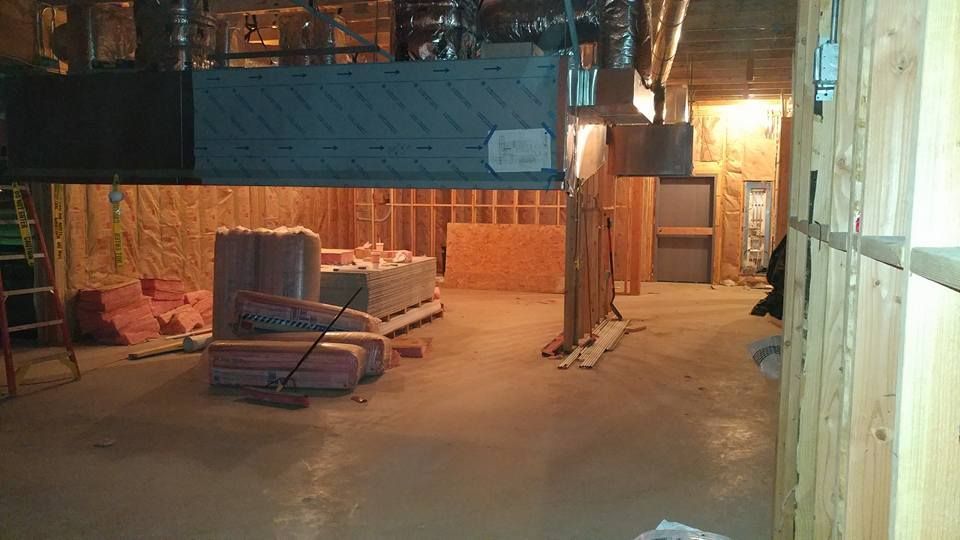 Basement under construction: insulation, wood framing, ductwork, and materials on the floor.