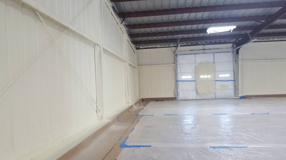 Interior of a building with spray foam insulation on the walls. The floor is covered in a protective layer.