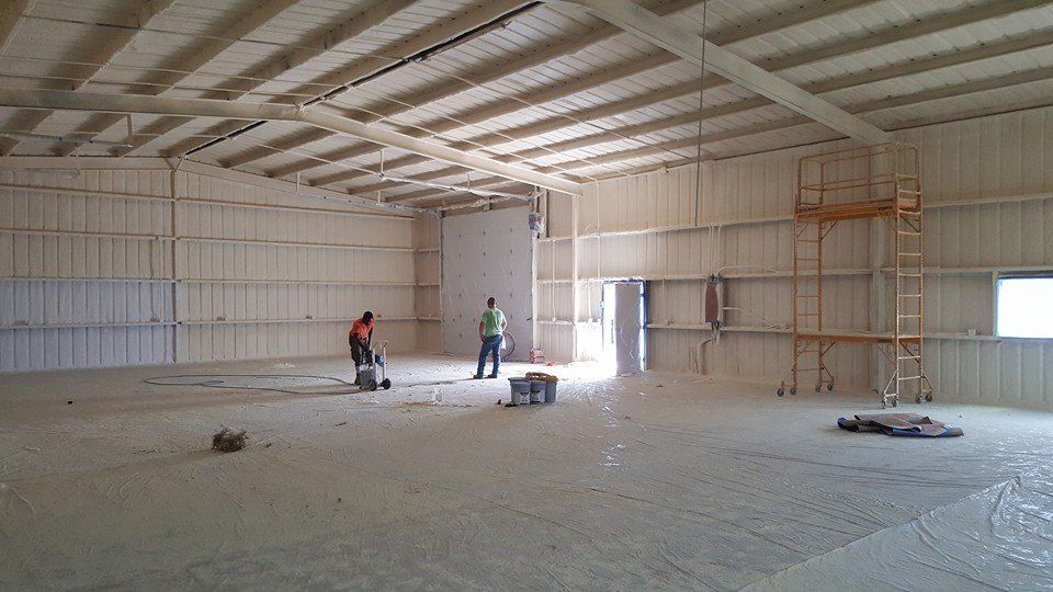 Warehouse interior with foam insulation. Two workers, equipment visible.