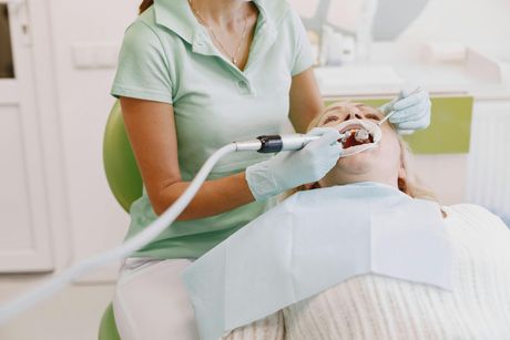 Dentist using a suction tool to treat a patient reclined in a dental chair