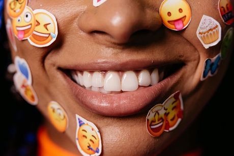Close-up of a smiling mouth with emoji stickers on the face