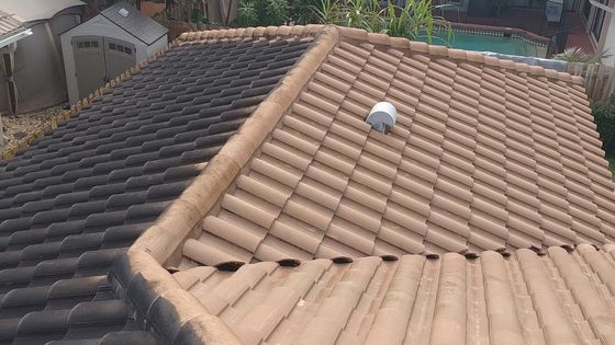 The roof of a house has two different colored tiles on it.