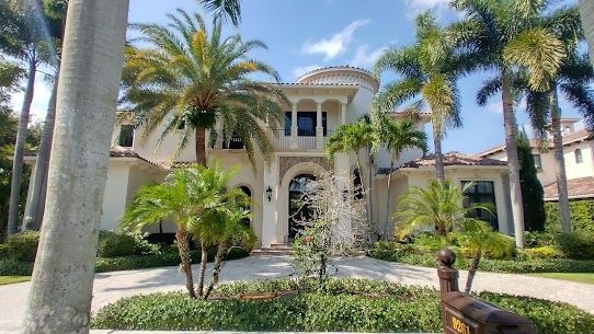 A large white house with palm trees in front of it.