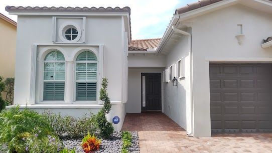 A white house with a garage and a brick driveway.