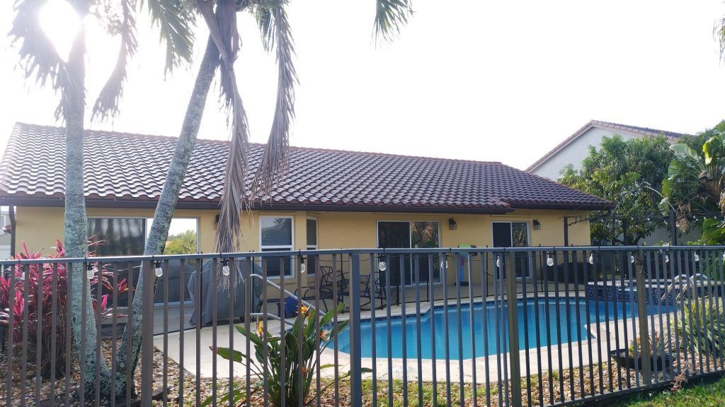 A house with a fence around it and a pool in front of it.
