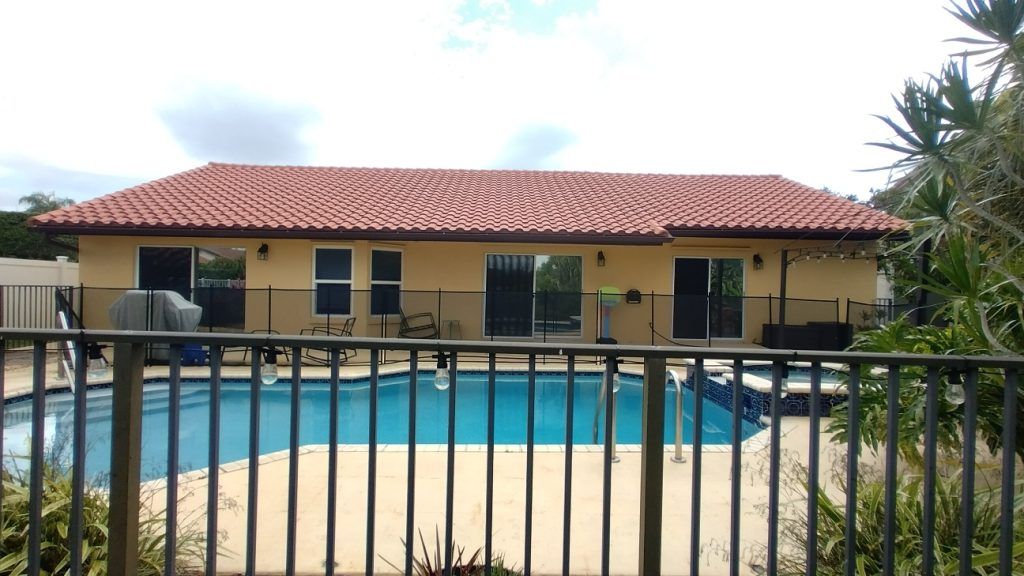 A large house with a pool behind a fence