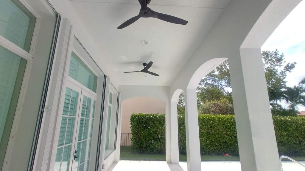 A ceiling fan is hanging from the ceiling of a porch
