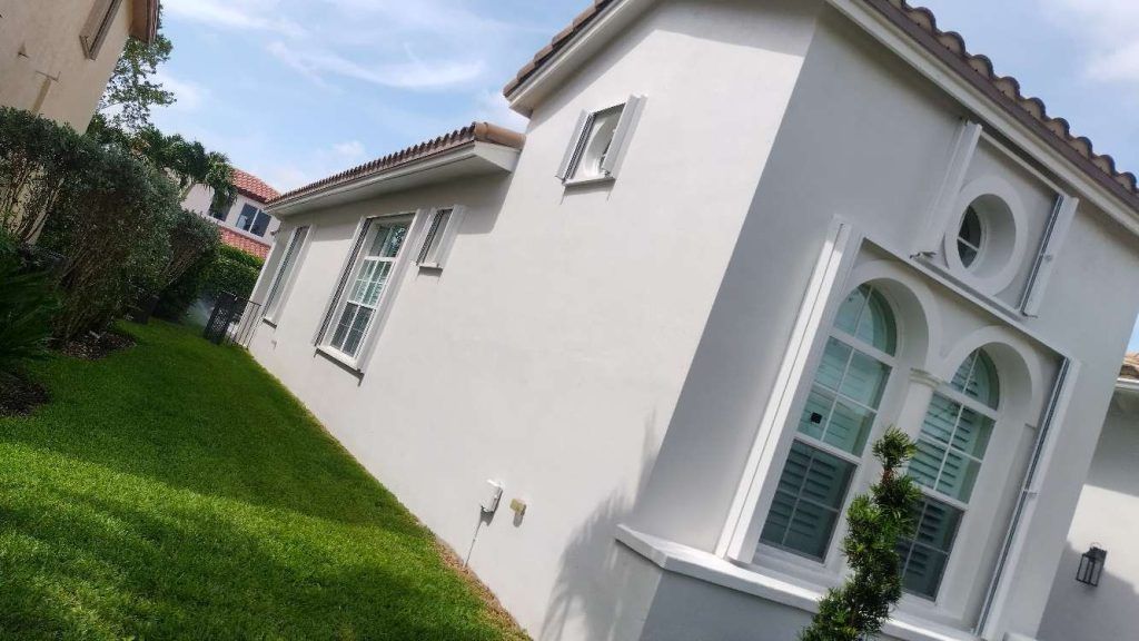 A white house with a lot of windows is sitting on top of a lush green lawn.