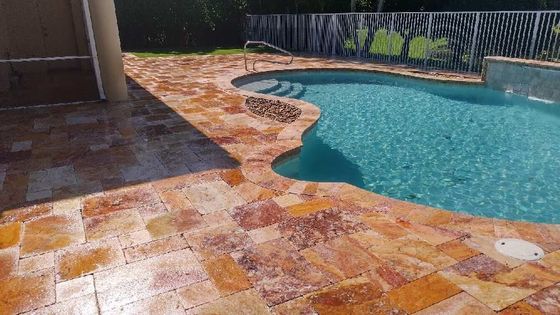 A large swimming pool with a tiled patio in front of it.