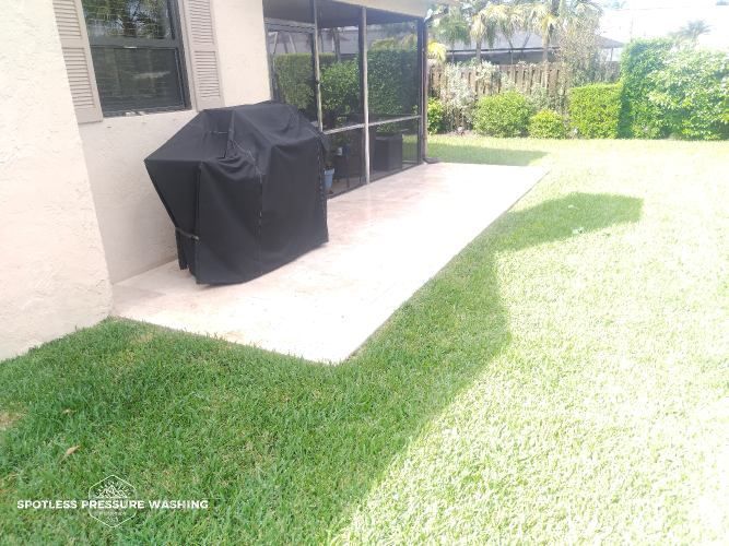 A black grill cover is sitting on a patio next to a house.