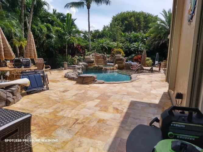 A patio with a pool in the background and a vacuum cleaner in the foreground.