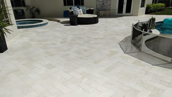 A patio with a couch and a pool in the background.