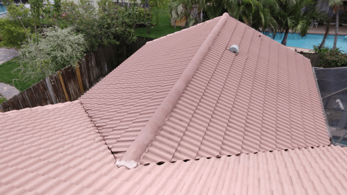 An aerial view of a roof of a house with a pool in the background.