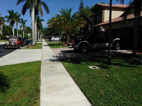 A truck is parked on the sidewalk in front of a house