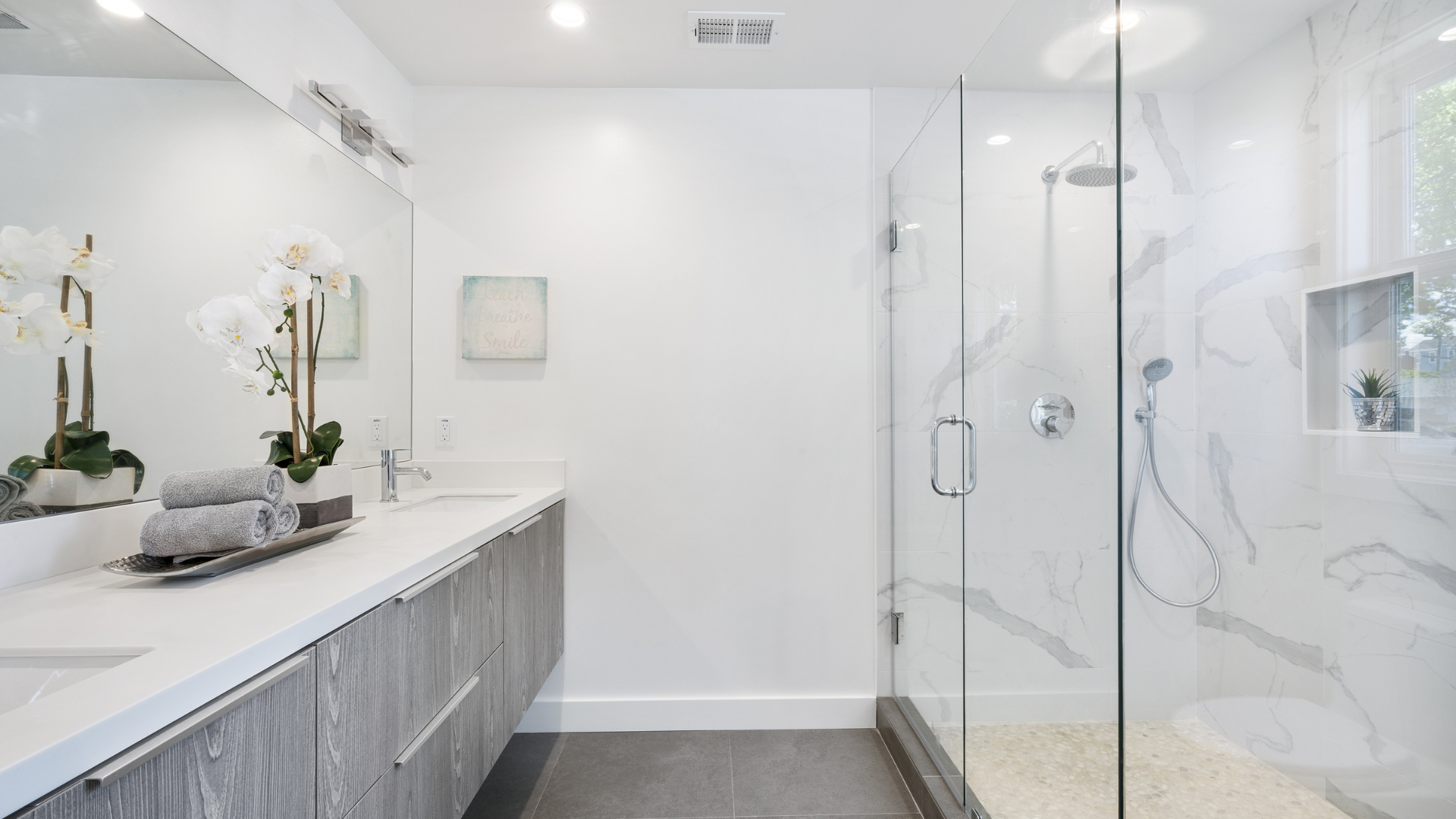 A bathroom with a walk in shower , sink and mirror.