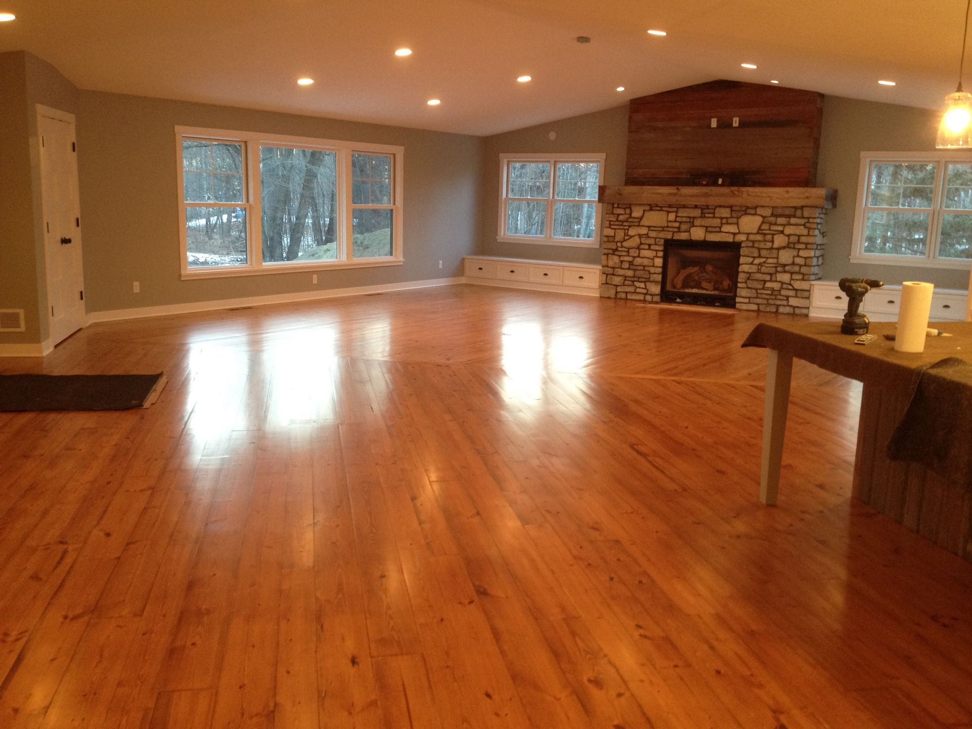 A living room with hardwood floors and a stone fireplace