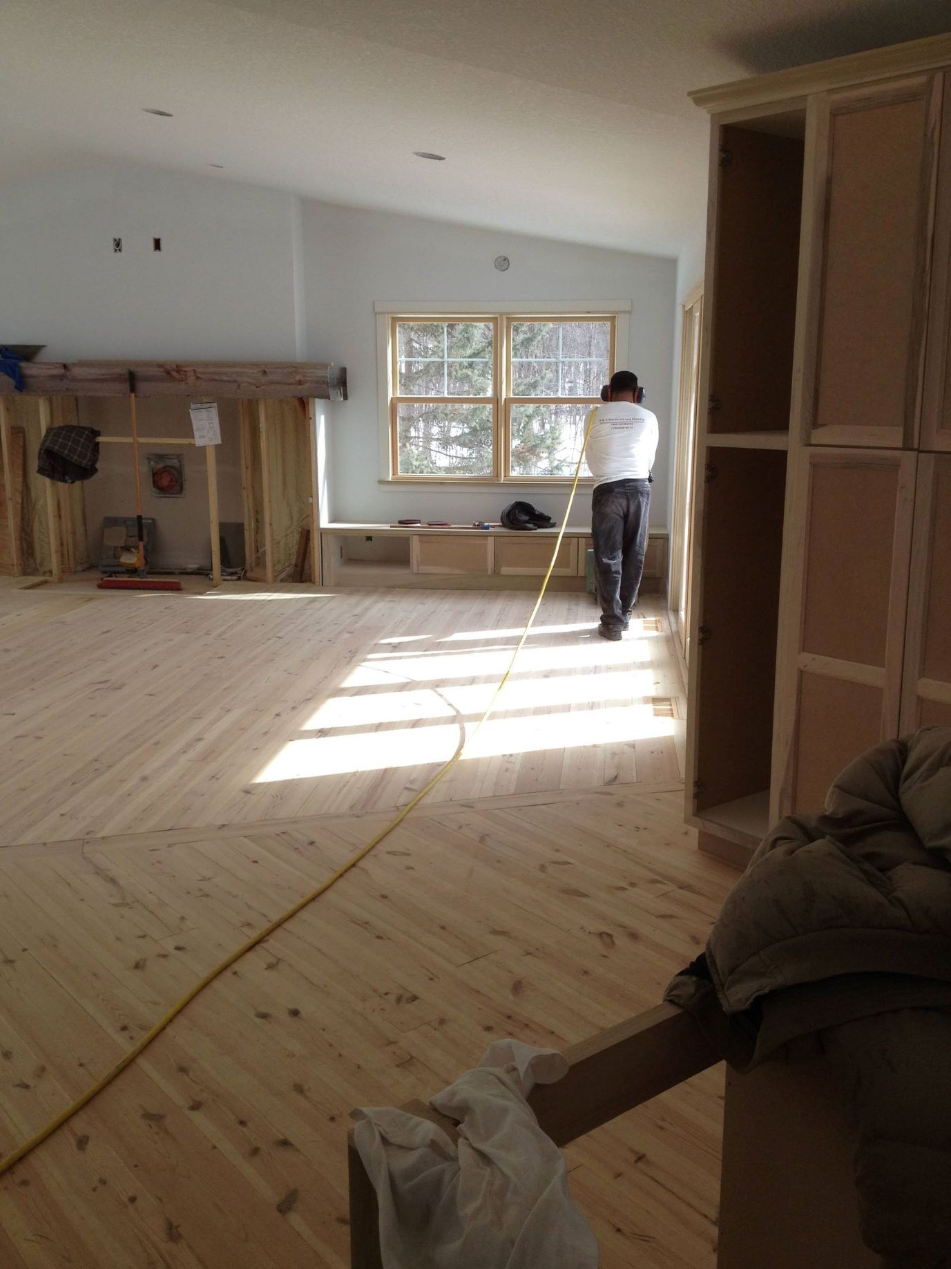 A man is working on a wooden floor in a room