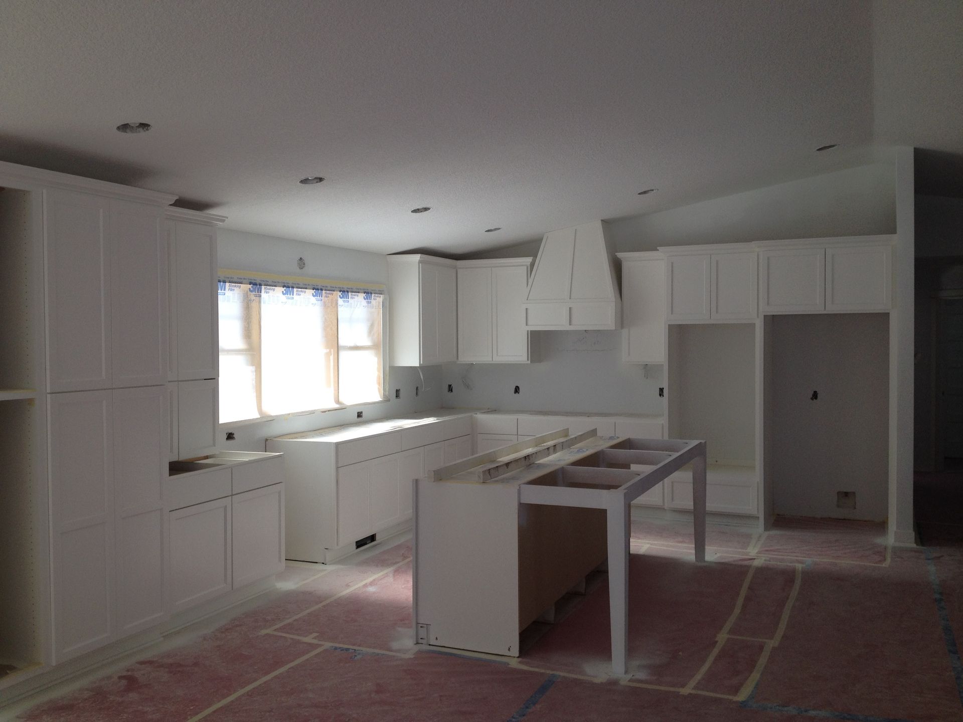 A kitchen under construction with white cabinets and a large island