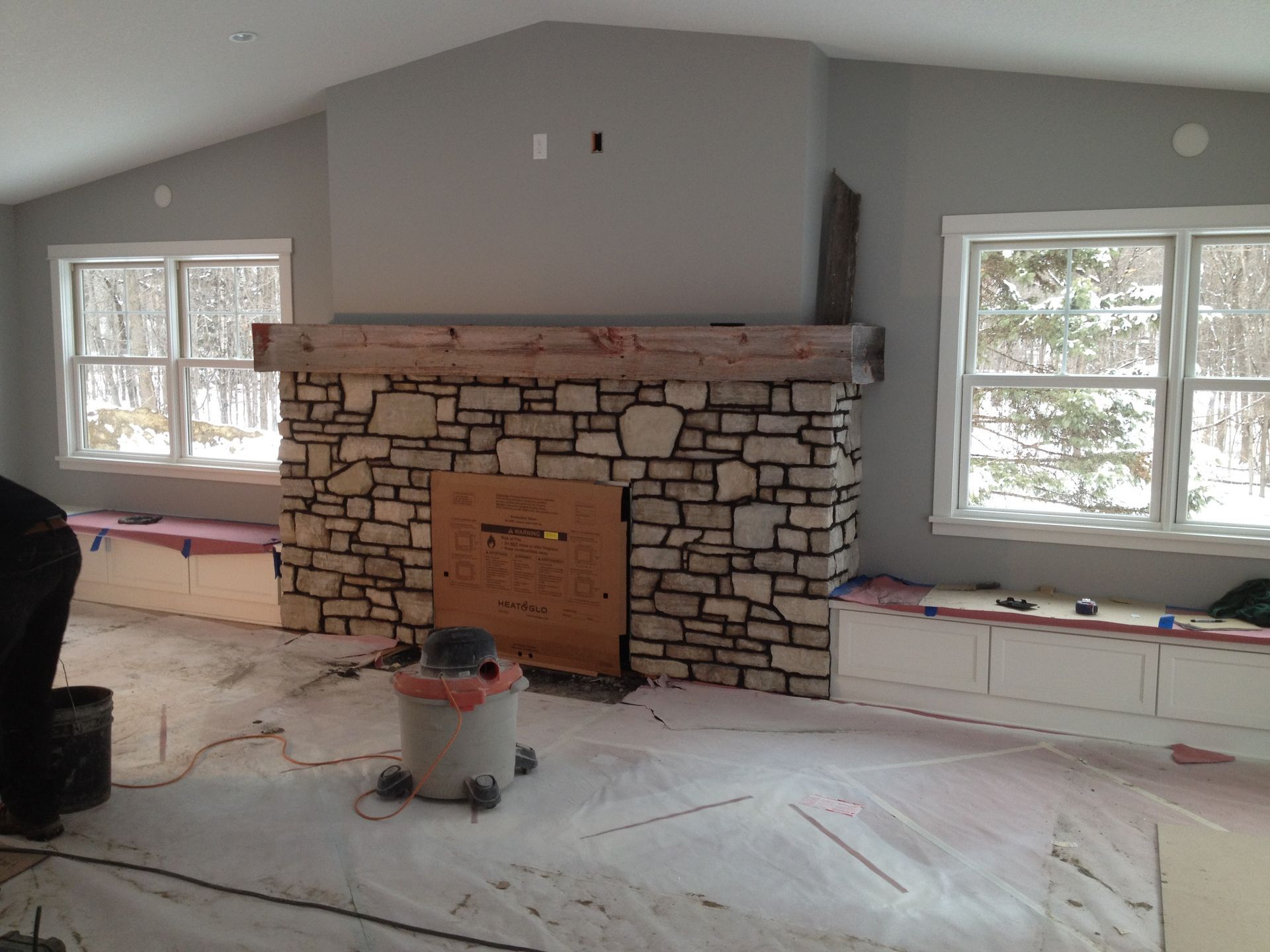 A room with a stone fireplace and a vacuum cleaner