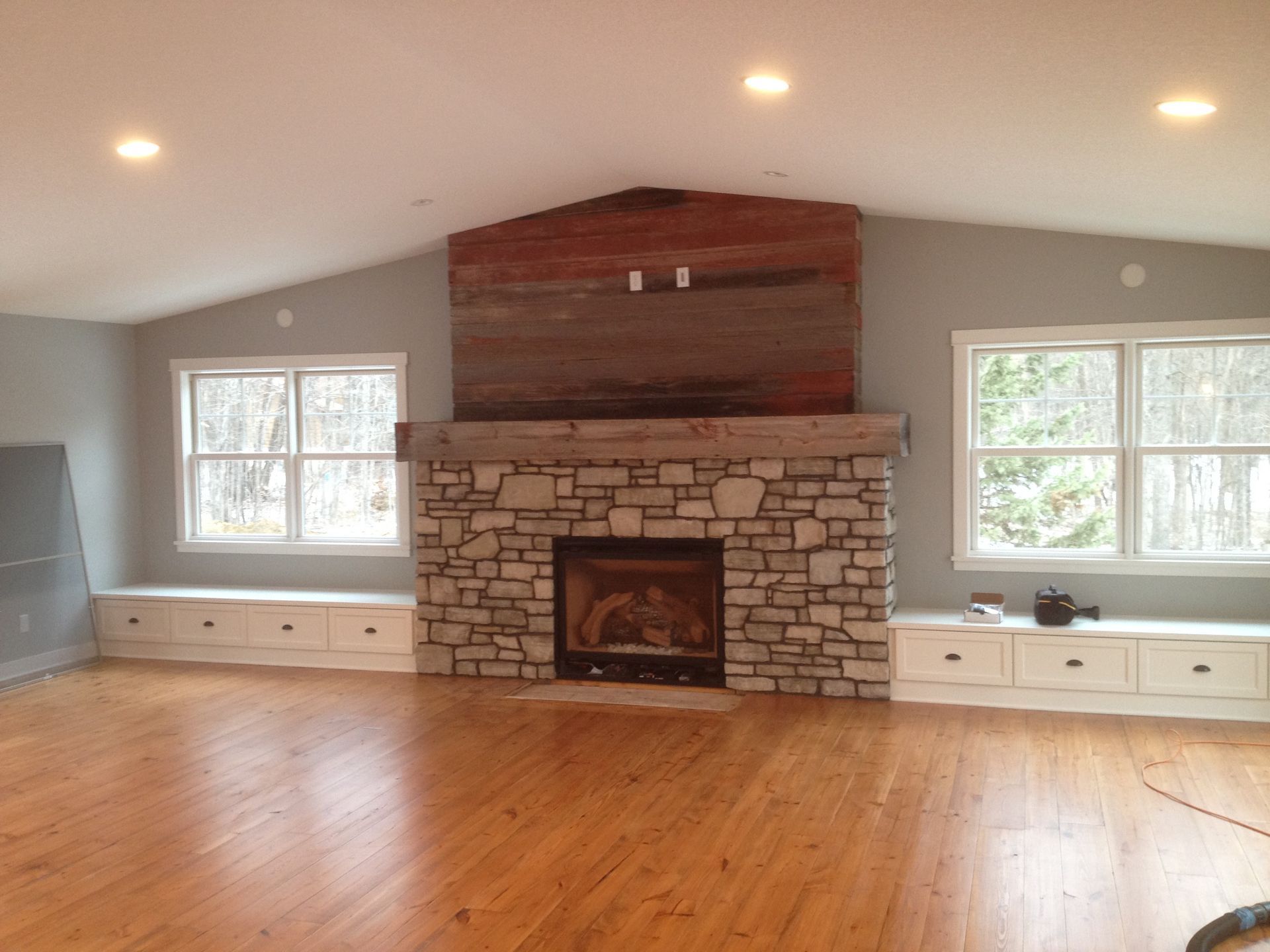 A living room with hardwood floors and a stone fireplace