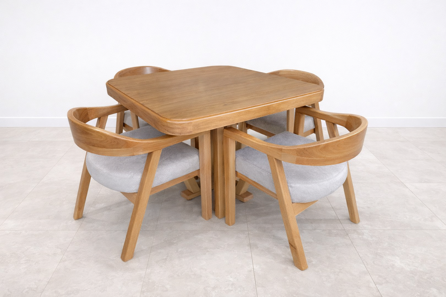 Mesa de comedor redonda de madera con cuatro sillas a juego sobre un suelo de baldosas claras.
