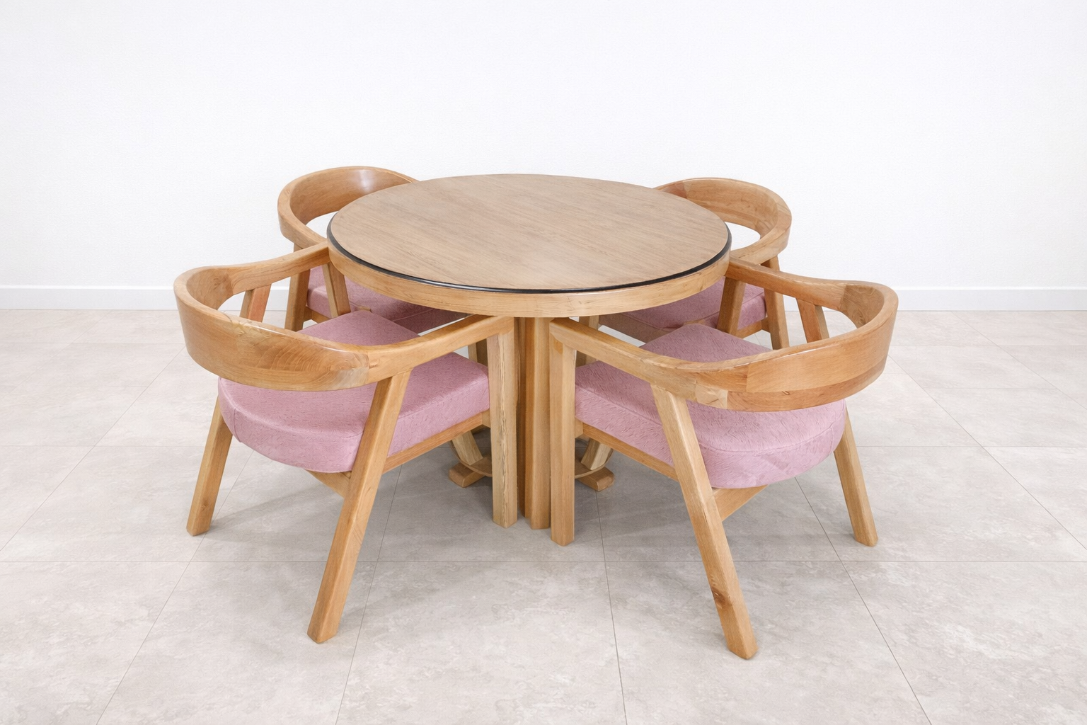 Mesa redonda de madera con cuatro sillas a juego y cojines rosas en una habitación luminosa.