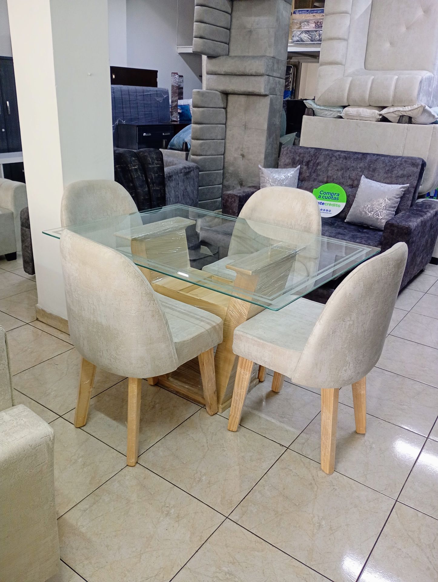 Mesa de comedor de cristal con cuatro sillas tapizadas en color crema