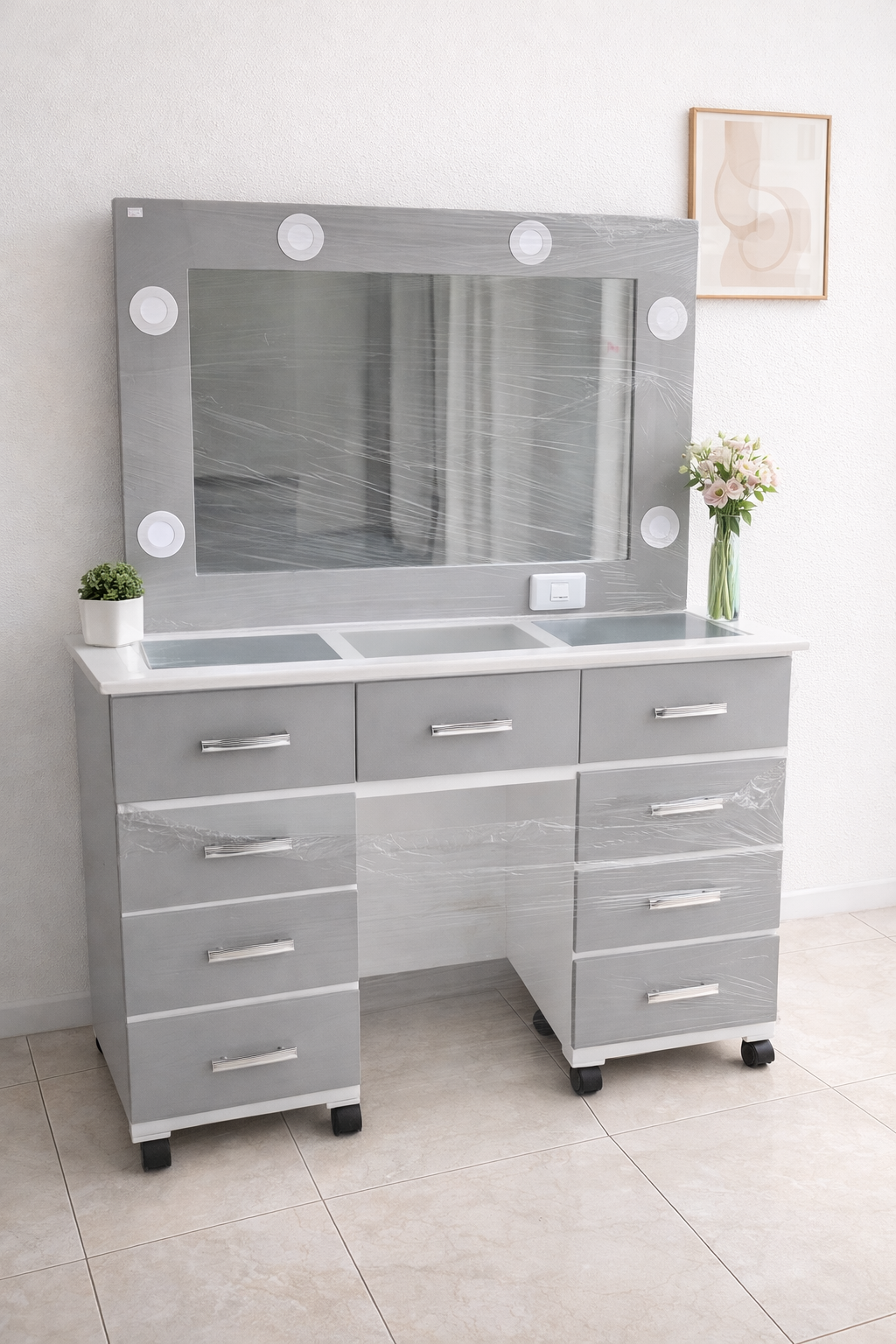 Elegante tocador blanco y dorado con espejo, silla y lámpara en una habitación luminosa.