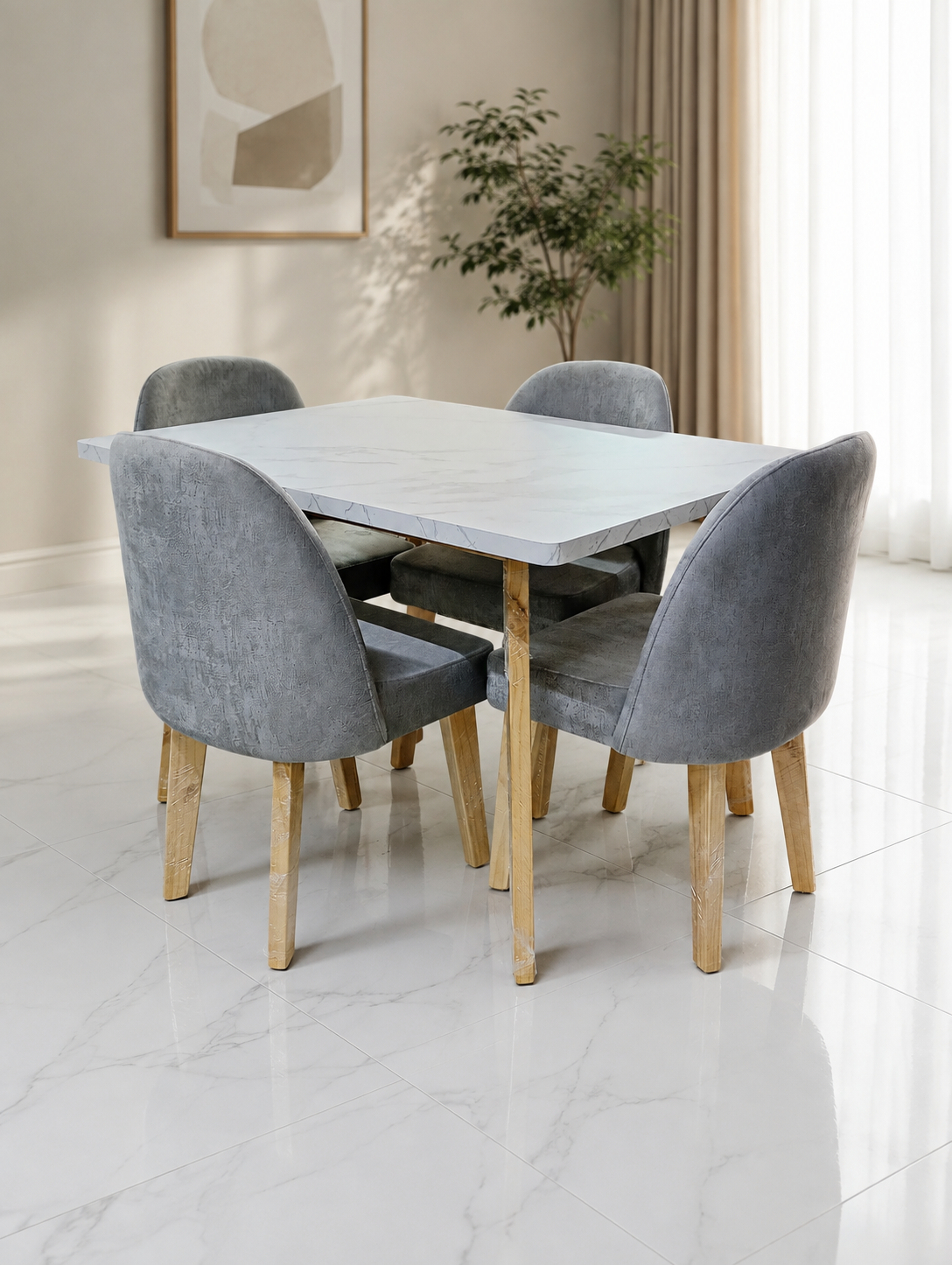 Sillas grises alrededor de una mesa de comedor blanca en una sala de exposición de muebles con sofás y espejos al fondo.