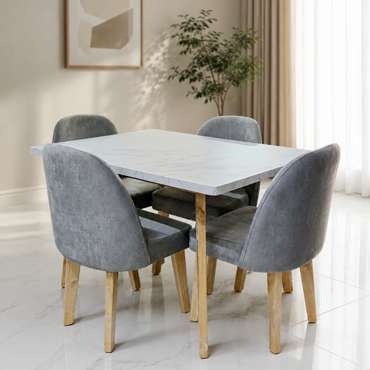 Sillas de comedor tapizadas en gris alrededor de una mesa blanca en una sala de exposición de muebles.