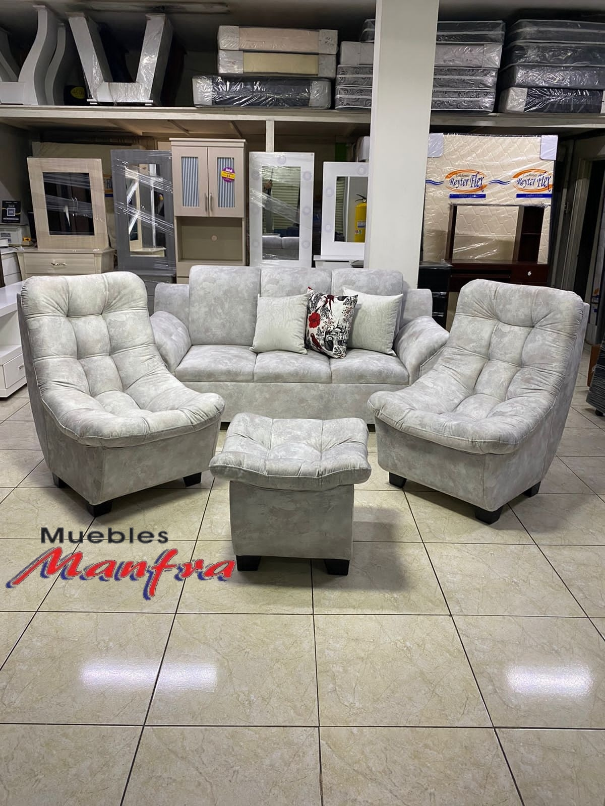 Conjunto de sofá blanco capitoné para salón con dos sillones y otomana en una exposición de muebles.
