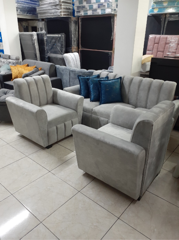 Sillones tapizados en gris y un sofá de dos plazas expuestos en la sala de exposición de una tienda de muebles.