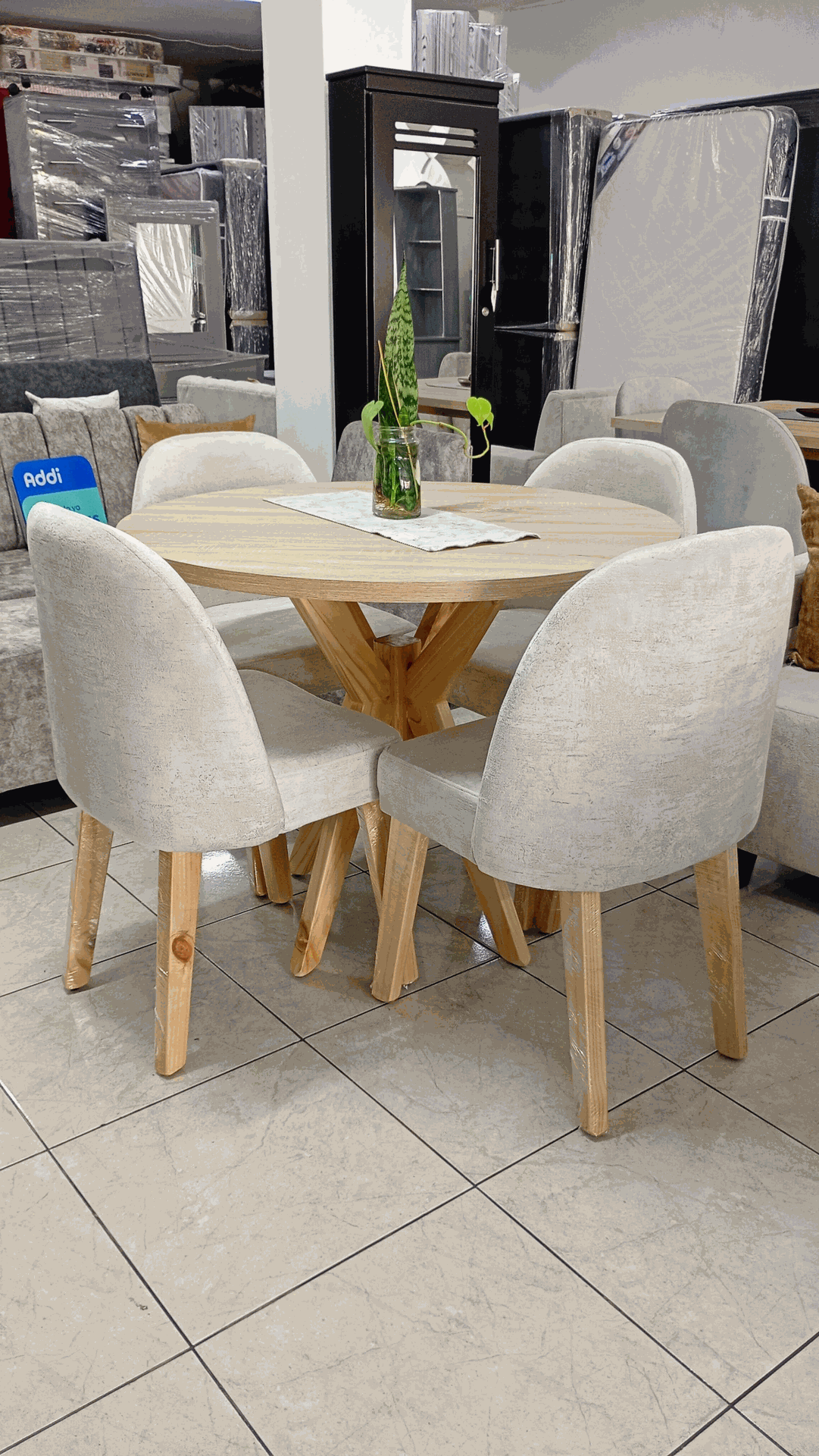 Mesa de comedor blanca con cuatro sillas acolchadas en una exposición de muebles.