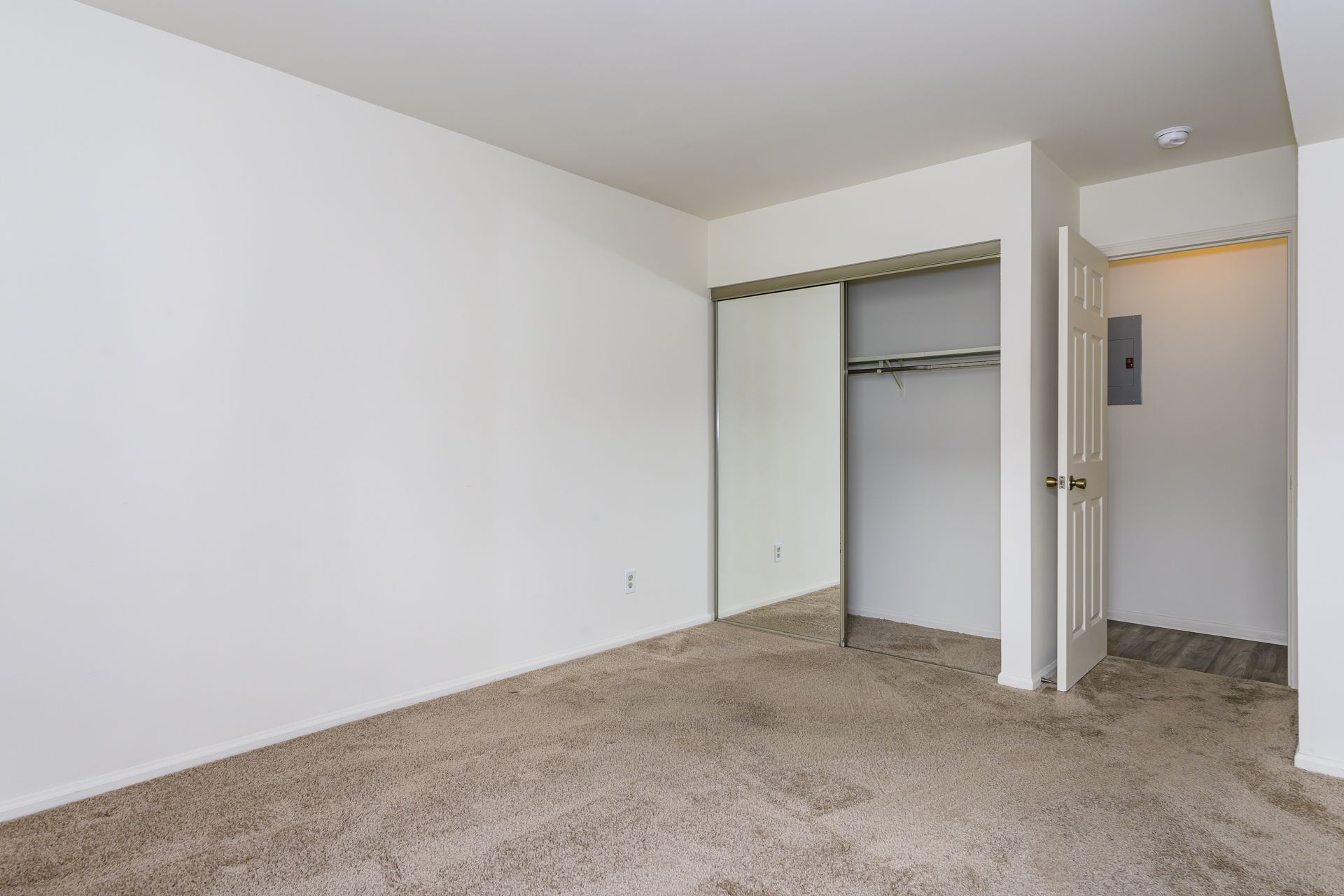 An empty bedroom with a closet and a sliding glass door.